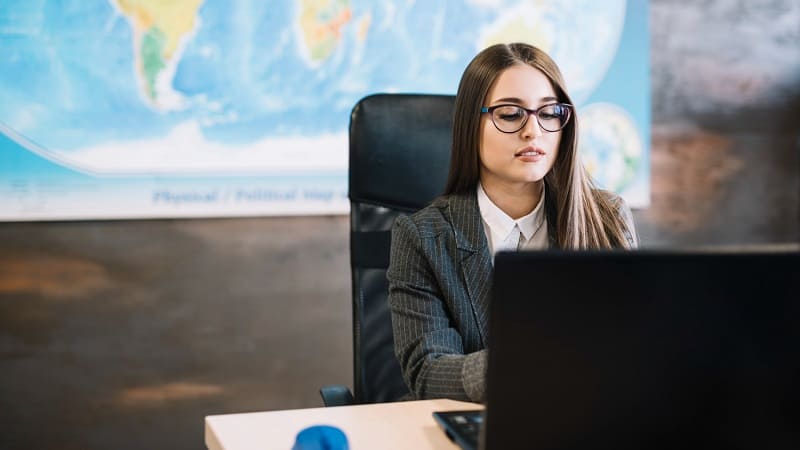 زن حرفه‌ای در حال کار با لپ‌تاپ در شرکت خارجی