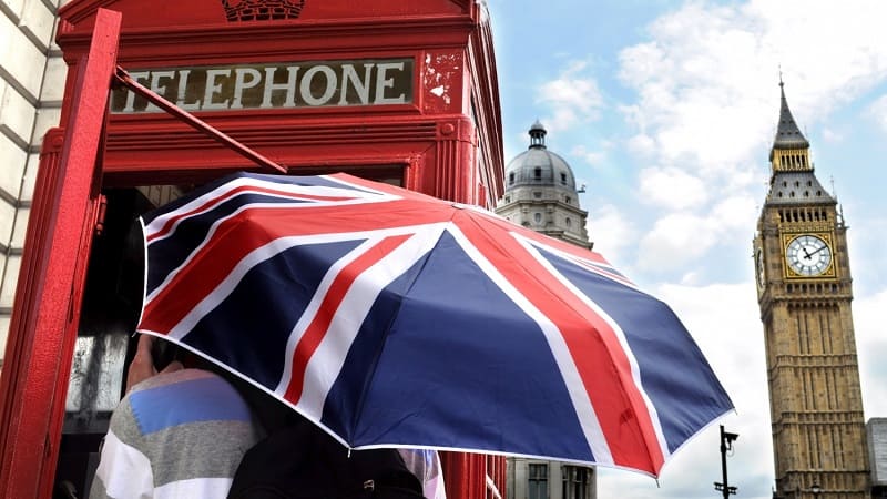 توریست زیر چتر با پرچم بریتانیا کنار بیگ بن